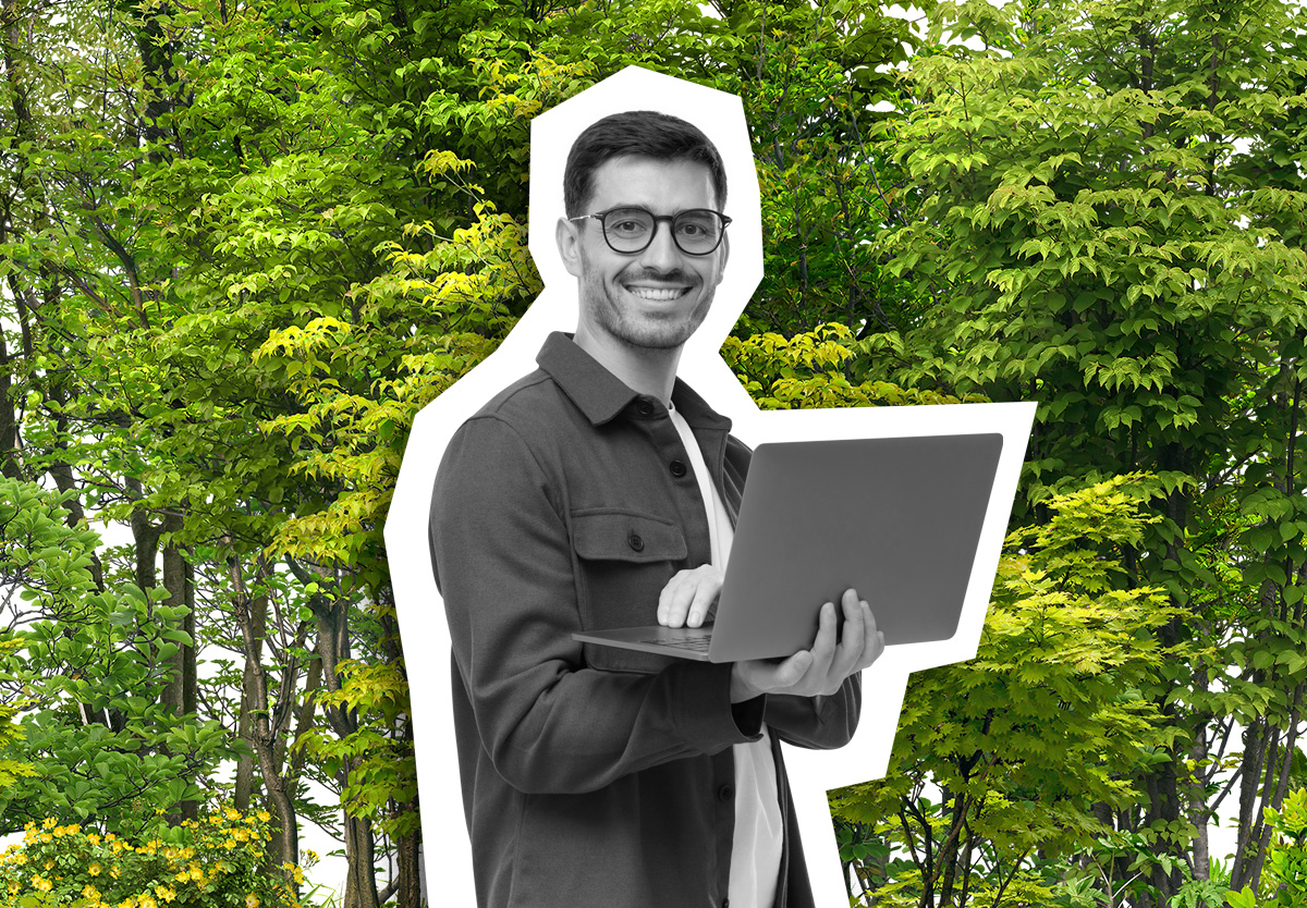 man holding laptop in front of foliage
