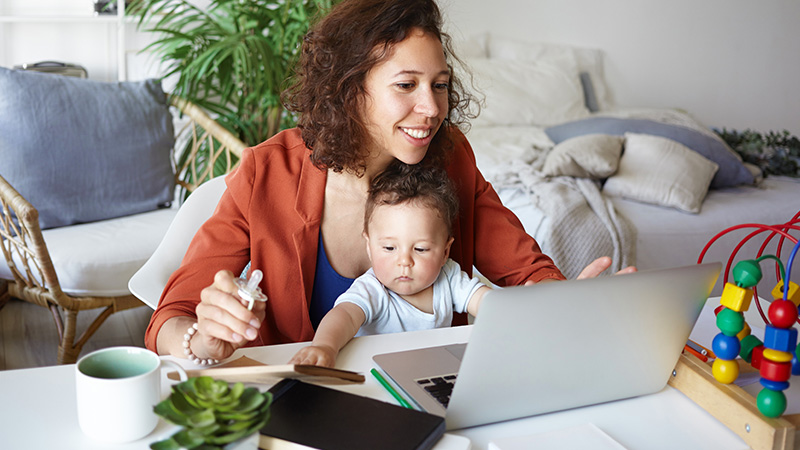 woman working from home with infant on lap