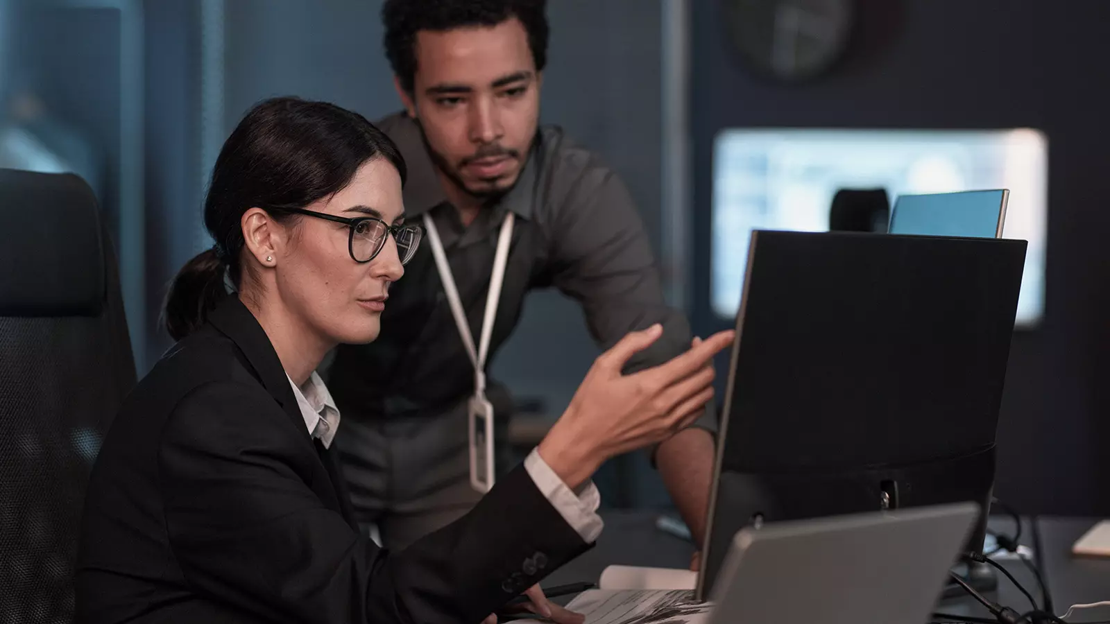 two coworkers discuss cybersecurity at a computer